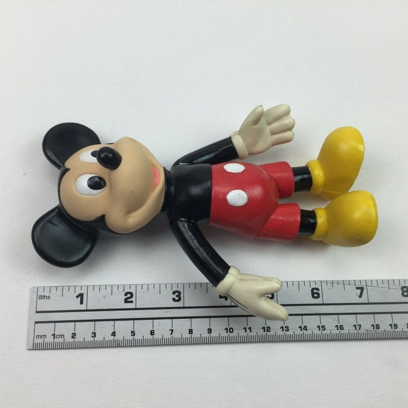 May include: A black and red plastic Mickey Mouse figurine with yellow shoes. The figurine is approximately 10 cm tall.