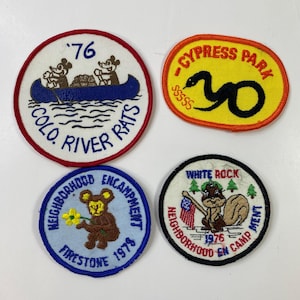 May include: Four vintage embroidered patches. One patch features Mickey Mouse in a canoe with the text "COLO. RIVER RATS" and "76". Another patch has a snake and the text "CYPRESS PARK". The other two patches have a bear and a squirrel with text.