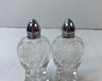 Salero y pimentero de cristal tallado con diseño texturizado y tapas de metal perforado de estilo vintage.
