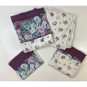 Puede incluir: Juego de ropa de cama floral. El juego incluye fundas de almohada y una sábana con un borde burdeos oscuro. El borde está adornado con grandes rosas coloridas y vegetación, y la tela principal tiene pequeñas flores rosas.