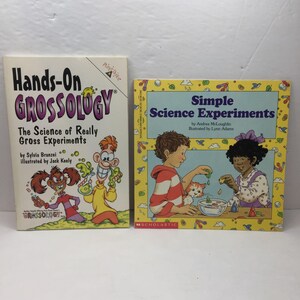 May include: Two children's books about science. The book on the left is titled "Hands-On Grossology: The Science of Really Gross Experiments" and features a cartoon illustration of a child with a microscope. The book on the right is titled "Simple Science Experiments" and features a cartoon illustration of two children conducting a science experiment.