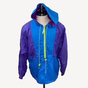 May include: A blue and purple hooded jacket with a neon green zipper and drawstrings. The jacket is made of a lightweight, water-resistant material.
