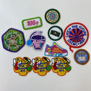 May include: A collection of embroidered patches with various designs and text. Patches include a sloth, a perfume bottle, a shoe, a trolley, and bees. Text includes "Swing Into Action!", "100+", "Pamper Me", "Girl Scouts", "Step It Up!", and "Catch the Reading Bug".