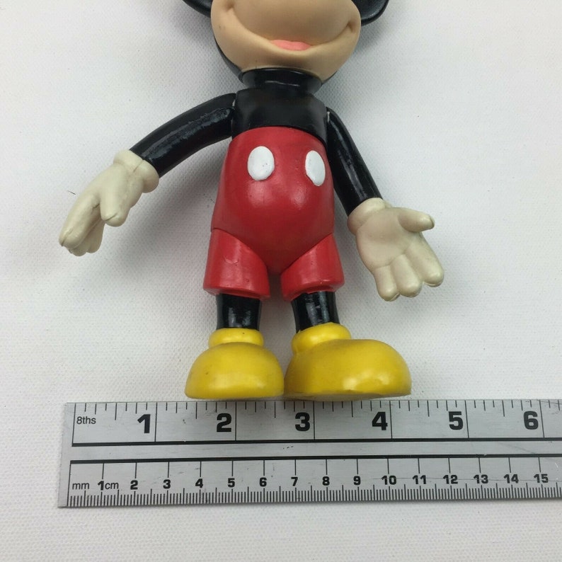 May include: A black and red plastic Mickey Mouse figurine with yellow shoes. The figurine is approximately 10 cm tall.