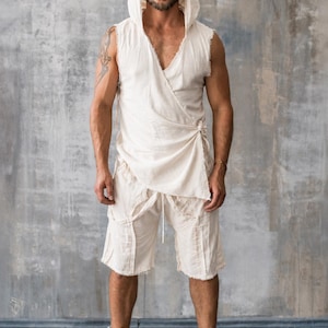 Puede incluir: Un top sin mangas color crema con capucha y cierre cruzado, combinado con shorts a juego. El conjunto se usa con zapatillas altas. El conjunto está hecho de una tela ligera y texturizada, lo que sugiere un estilo bohemio casual.