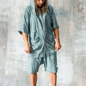 Puede incluir: Conjunto de chaqueta con capucha y pantal&oacute;n corto de color verde azulado claro. La chaqueta tiene mangas cortas, m&uacute;ltiples bolsillos y cierre de bot&oacute;n. El pantal&oacute;n corto es holgado. El conjunto se combina con zapatillas altas verde oliva con hebillas plateadas.