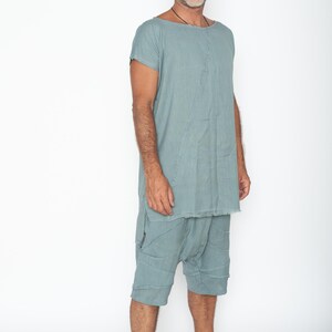 Puede incluir: Conjunto de t&uacute;nica y pantal&oacute;n corto de lino verde azulado claro. La t&uacute;nica tiene cuello barco y mangas cortas. El pantal&oacute;n corto llega a la rodilla con un corte relajado. La tela parece tener un aspecto texturizado y lavado. El conjunto lo lleva una persona.