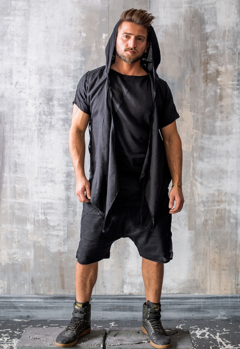 Puede incluir: Top negro con capucha y mangas cortas con pantalones cortos a juego. El conjunto tiene un dise&ntilde;o en capas con una parte delantera drapeada. El modelo lleva zapatillas altas negras.