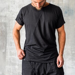 May include: Black t-shirt and shorts set. The t-shirt has a diagonal seam across the front. The shorts have a unique design with multiple seams. The clothing appears to be made of a soft, flowing fabric.