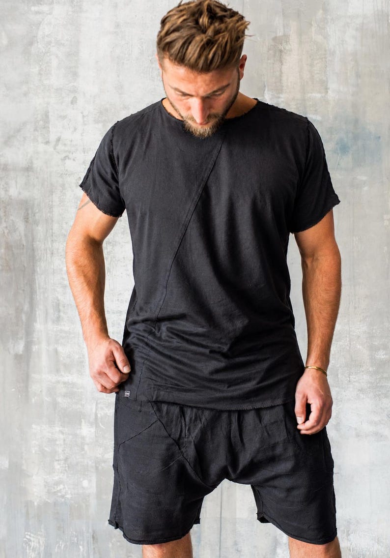 May include: Black t-shirt and shorts set. The t-shirt has a diagonal seam across the front. The shorts have a unique design with multiple seams. The clothing appears to be made of a soft, flowing fabric.
