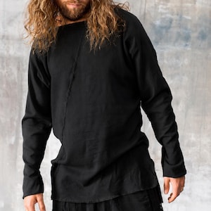 May include: Black long-sleeve shirt and matching pants. The shirt has a unique square neckline and a vertical seam down the front. The pants have a relaxed fit. The outfit is made of a soft, flowing fabric.