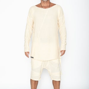 Puede incluir: Conjunto de camisa y pantal&oacute;n corto de lino color crema. La camisa tiene cuello barco y una costura diagonal en la parte delantera. El pantal&oacute;n corto tiene un dise&ntilde;o en capas. El conjunto lo lleva una persona.