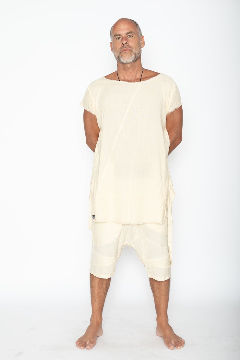 Puede incluir: Un conjunto de t&uacute;nica y pantal&oacute;n corto de lino color crema. La t&uacute;nica tiene mangas cortas y una costura diagonal &uacute;nica. El pantal&oacute;n corto llega a la rodilla con un dise&ntilde;o de patchwork. El conjunto lo lleva una persona sobre fondo blanco.