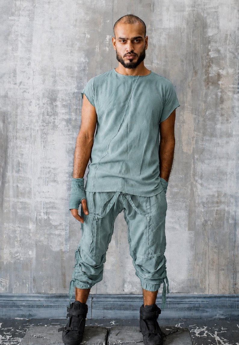 May include: A person in a light teal linen outfit, comprising a short-sleeved top and cropped trousers with tie details. They are also wearing black high-top boots.