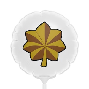 May include: A white, round balloon with a gold and brown leaf-like design in the center. The design is outlined in black. The balloon is attached to a white stick.