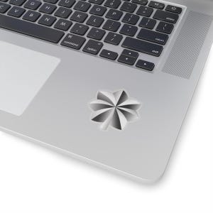 May include: A silver and white sticker in a starburst design is affixed to a laptop. The sticker has a white border and a radial pattern of alternating silver and white segments. The laptop's keyboard and trackpad are also visible.