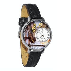 May include: A silver-toned wristwatch with a black leather band. The watch face features a violin, musical notes, and a clock face with black numerals. The watch has a quartz movement.
