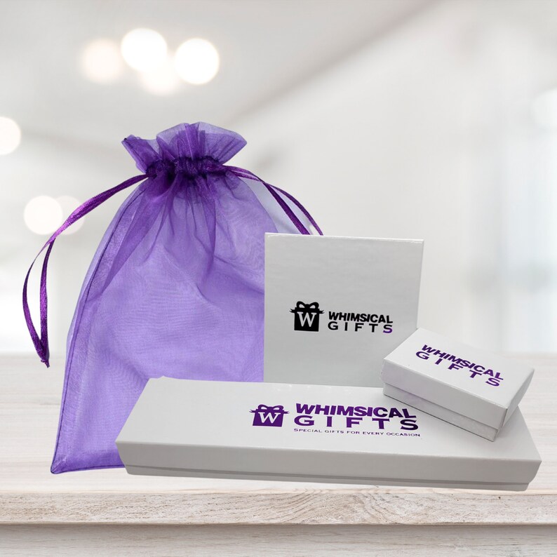 K&ouml;nnte beinhalten: Eine Auswahl an wei&szlig;en Geschenkboxen mit dem Logo "Whimsical Gifts" in Lila und Schwarz, sowie ein violetter Organzabeutel. Der Beutel ist transparent und hat einen Kordelzug, ideal f&uuml;r kleine Geschenke.