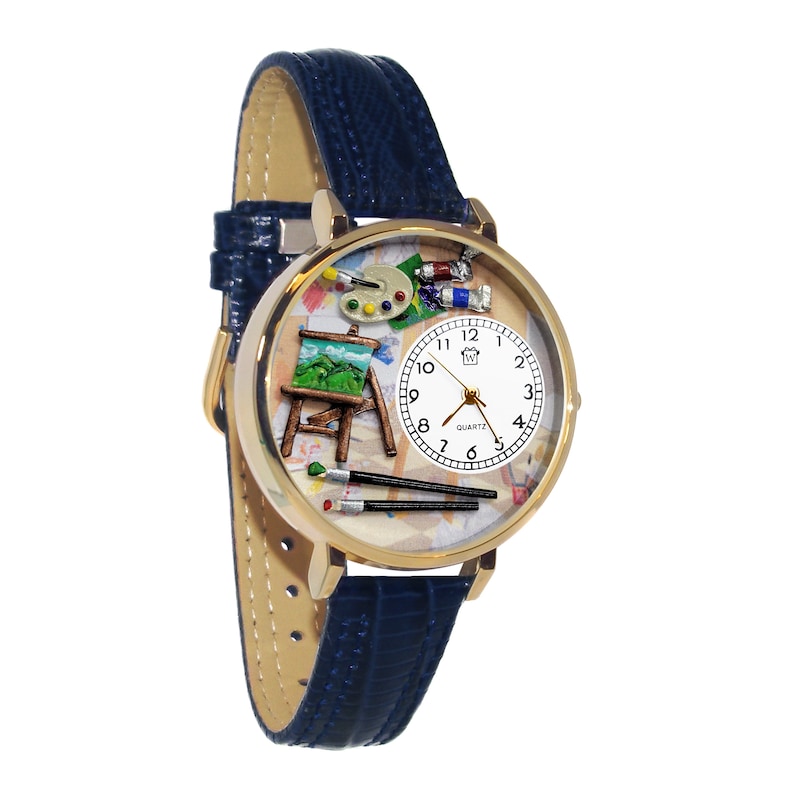 May include: Gold-tone quartz watch with a blue leather band. The watch face features a miniature artist's easel, paint tubes, palette, and brushes. The watch has a white face with black numerals and hands.