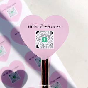 May include: Pink heart-shaped sticker with the text "BUY THE Bride A DRINK?" and a QR code with a green dollar sign in the center.