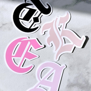 May include: Four die-cut stickers in a gothic font style. The stickers are in black, light pink, and hot pink colors. The stickers spell out the letters "CA" and "A". The text "littlemagicprints" is at the bottom.