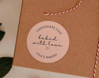 Puede incluir: Pegatina redonda rosa con el texto "Chocolate Chip baked with love" y un pequeño símbolo de corazón. Debajo del texto está "Lila's Bakery".
