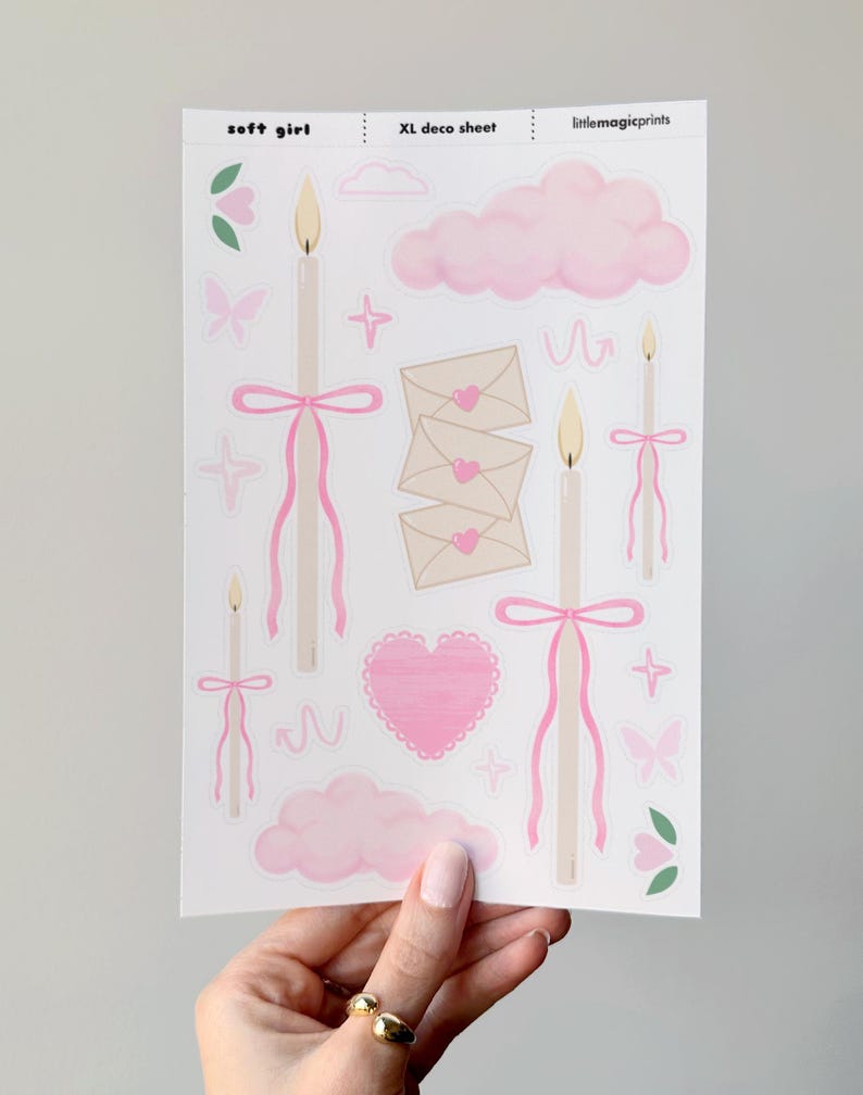 Puede incluir: Una hoja de pegatinas con tem&aacute;tica de chica suave. Las pegatinas incluyen velas con lazos rosas, nubes rosas, sobres con corazones, mariposas y flores. El texto "soft girl" y "XL deco sheet" son visibles.