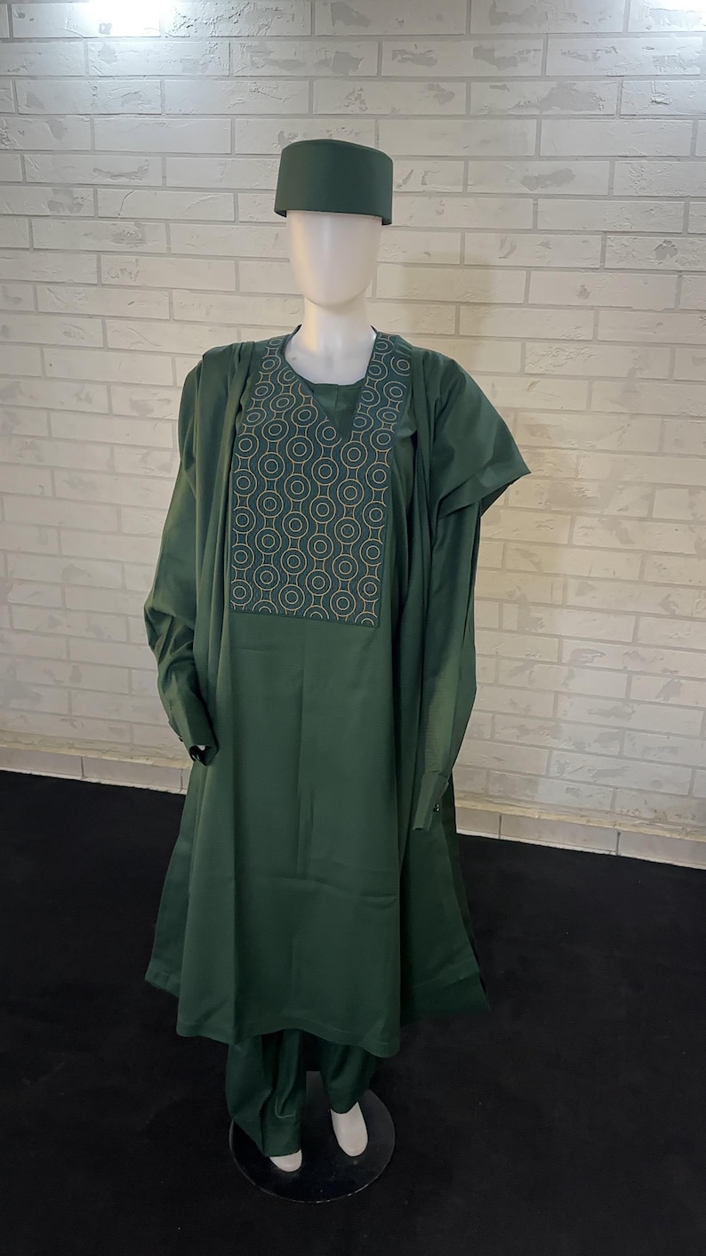 Pode incluir: Um conjunto de tr&ecirc;s pe&ccedil;as verde escuro com um padr&atilde;o geom&eacute;trico no peito. O conjunto inclui uma camisa de manga comprida, cal&ccedil;as e um chap&eacute;u.