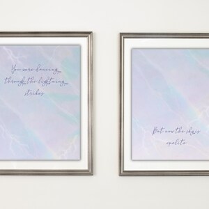 K&ouml;nnte beinhalten: Zwei gerahmte Kunstdrucke mit silberfarbenen Rahmen. Jeder Druck hat einen pastellfarbenen Hintergrund mit Aquarelleffekt und Text. Einer lautet "You were dancing through the lightning strikes". Der andere lautet "But now the sky is opalite."
