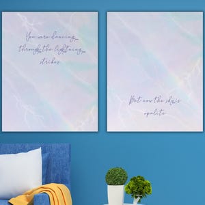K&ouml;nnte beinhalten: Zwei gerahmte Kunstdrucke mit einem Hintergrund im Aquarellstil in Blau-, Lila- und Wei&szlig;t&ouml;nen. Der linke Druck tr&auml;gt den Text "You were dancing through the lightning strikes". Der rechte Druck lautet "But now the sky is opalite."