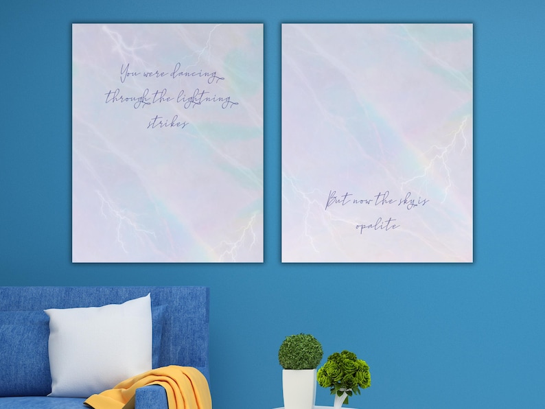 K&ouml;nnte beinhalten: Zwei gerahmte Kunstdrucke mit einem Hintergrund im Aquarellstil in Blau-, Lila- und Wei&szlig;t&ouml;nen. Der linke Druck tr&auml;gt den Text "You were dancing through the lightning strikes". Der rechte Druck lautet "But now the sky is opalite."