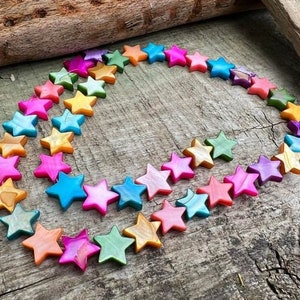 May include: A strand of colourful star-shaped beads made of iridescent shell. The beads are strung on a clear elastic cord and are perfect for making jewellery.