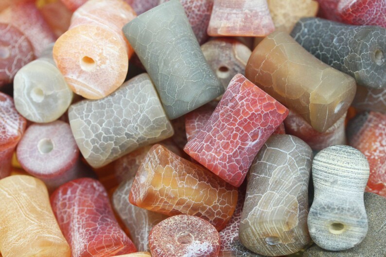 May include: A collection of agate beads in various colours and patterns, including red, orange, brown, and grey. The beads are smooth and polished, with a natural, organic look.