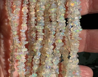 May include: A strand of iridescent white opal chip beads. The beads are small and irregular in shape, with a translucent, glassy appearance. The strand is approximately 18 inches long.
