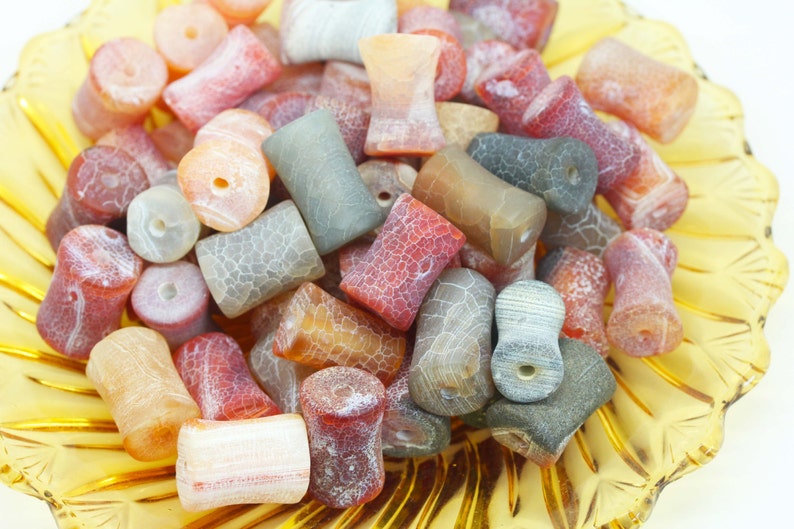 May include: A collection of colourful agate beads in various shades of red, orange, brown, and grey. The beads are smooth and polished, with a natural, organic look. They are perfect for jewellery making or other craft projects.