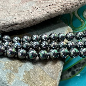 May include: A strand of iridescent black beads. The beads are round and have a smooth, glossy finish.