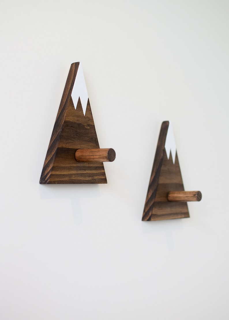 May include: Two wooden mountain-shaped wall hooks with a white painted snow cap and a brown wooden peg.