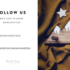 May include: A wooden mountain-shaped coat rack with white painted peaks. The rack has two hooks and is displayed on a brown fabric background. The text "FOLLOW US" is displayed in black text on a white background. The text "WE'D LOVE TO SHARE MORE WITH YOU" is displayed in black text on a white background. The text "@HACHIANDTEGS" is displayed in black text on a white background. The text "FACEBOOK.COM/HACHIANDTEGS" is displayed in black text on a white background. The text "Hachi+tegs HANDMADE" is displayed in gray text on a white background.