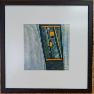 Könnte beinhalten: Ein gerahmtes abstraktes Kunstwerk mit Patchwork-Design. Das Kunstwerk zeigt verschiedene Blautöne und Grüntöne mit Akzenten in Gelb und Orange. Das Stück ist in einem schwarzen Rahmen gerahmt.