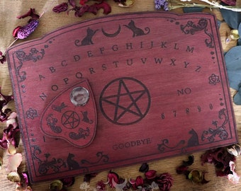 Red wooden ouija board adorned with cats and victorian ornaments, spirit planchette