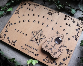 May include: Wooden Ouija board with a planchette, alphabet, numbers, and the words "Yes", "No", and "Goodbye". The board is decorated with ivy.