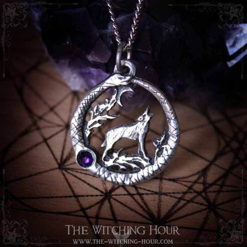 Puede incluir: Collar con colgante de plata que representa un lobo aullando a la luna, rodeado de una serpiente y una luna creciente. El colgante tiene una piedra preciosa p&uacute;rpura en el centro.