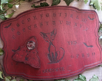 Red ouija board adorned with a gothic cat and bats made from wood, talking spirit board for spiritualism, occult arts, witchcraft decor
