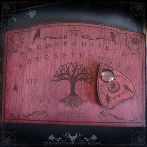 Red wooden ouija board adorned with ravens and tree of life Yggdrasil, spirit planchette