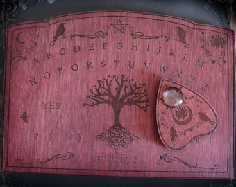 Red wooden ouija board adorned with ravens and tree of life Yggdrasil, spirit planchette