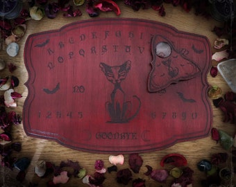 Red wooden ouija board adorned with an evil sphynx cat and bats, spirit board