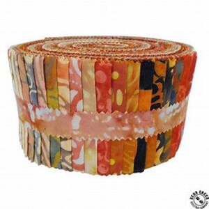 May include: A roll of fabric scraps in various shades of orange, yellow, and brown with a batik pattern. The fabric is rolled up and tied with a white ribbon.