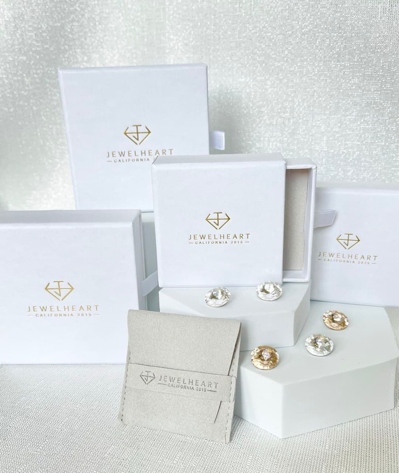 May include: Four white boxes with the logo 'Jewelheart - California 2013' and a small white pouch with the same logo. The boxes are arranged in a pyramid shape with the pouch in front.