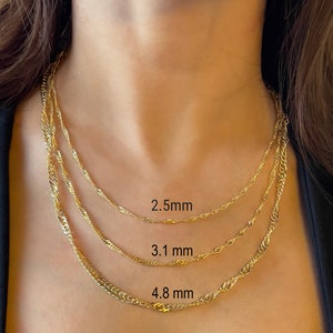 14K gold singapore chain necklaces of different thicknesses, layered on a person's neck. The chains are 2.5 mm, 3.1 mm, and 4.8 mm thick.