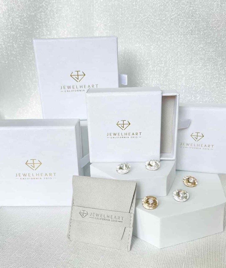 May include: Four white boxes with the logo 'Jewelheart - California 2013' and a small white pouch with the same logo. The boxes are arranged in a pyramid shape with the pouch in front.